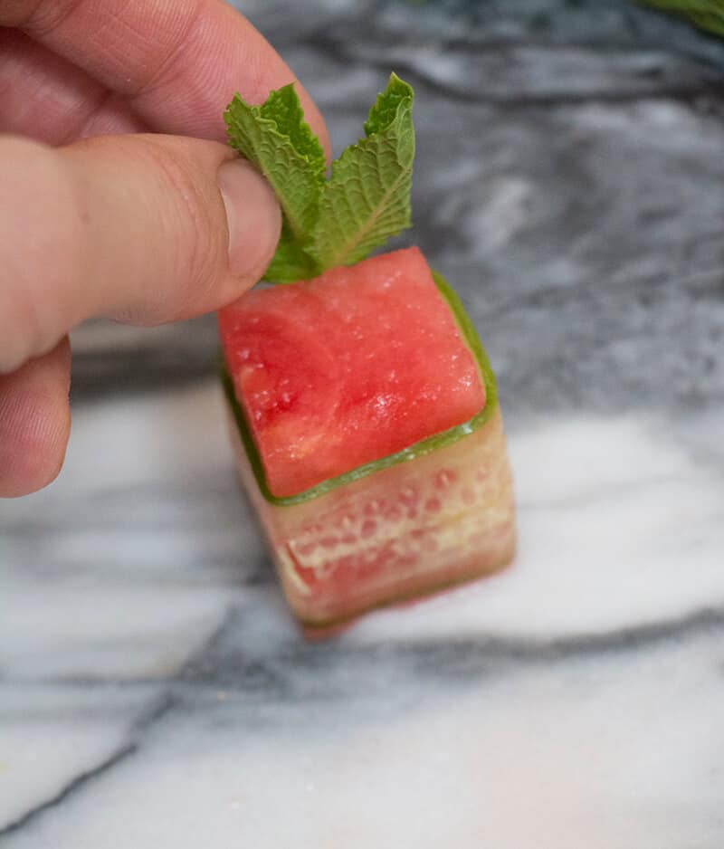 A process shot of a watermelon canapé being made.