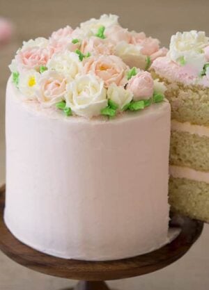 A photo of a cake with buttercream roses on top.