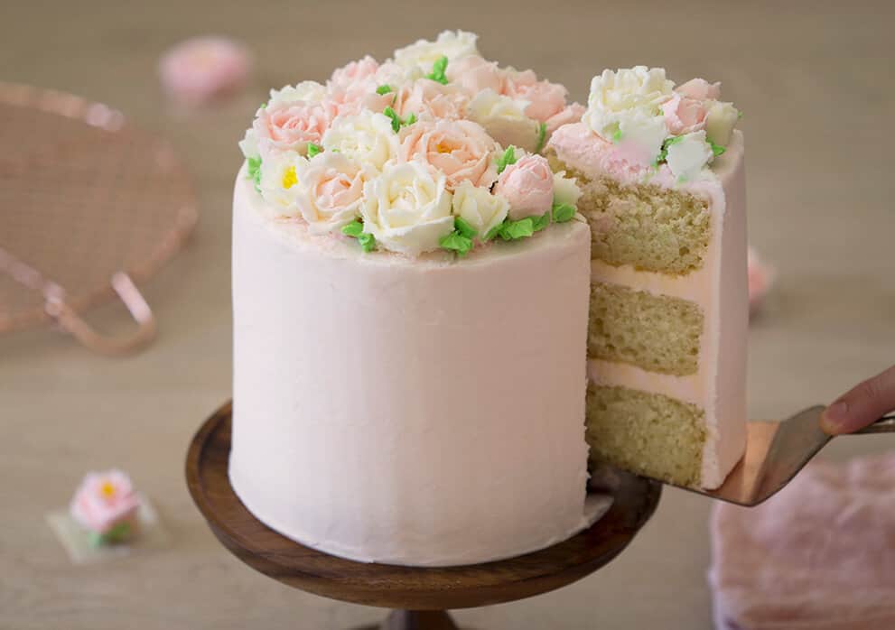 A photo of a cake with buttercream roses on top.