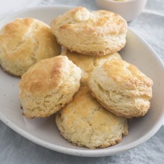 A photo of a plate of buttermilk biscuits on a light pink bowl on top of a blue napkin