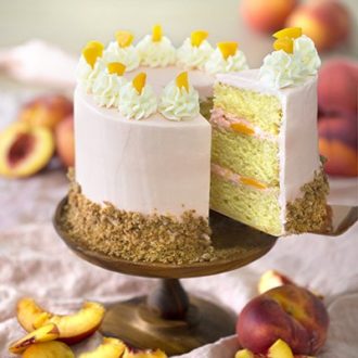 Photo of a peach cake with a piece being removed