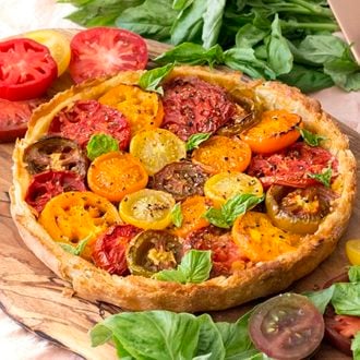 A tomato tart on a wood board with fresh basil.