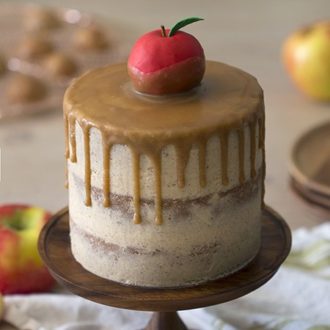 A caramel apple cake on a wooden cake plate.