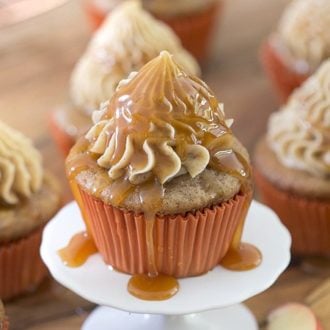 An apple cupcake with frosting and caramel drizzled on top.