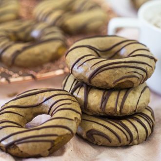 A stack of pumpkin spice donuts with chocolate drizzled on top.
