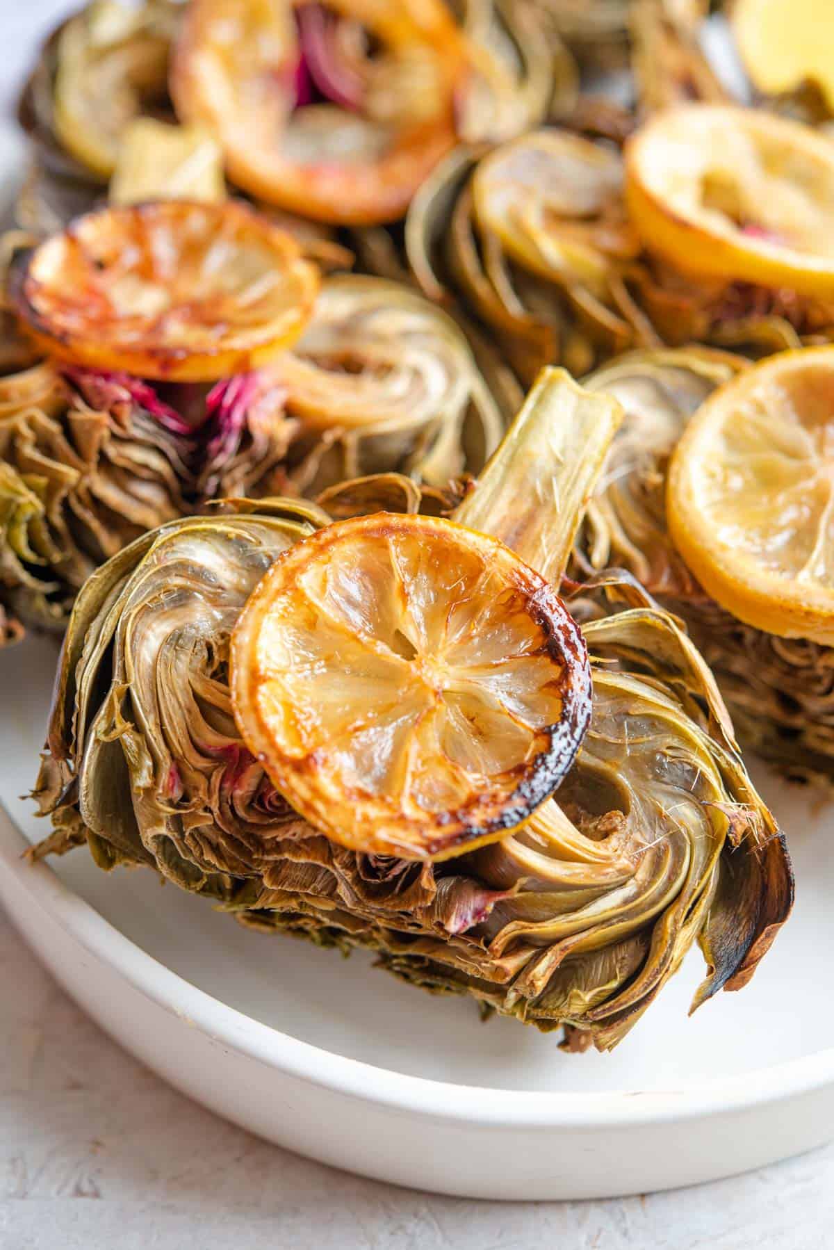 A close up of a roasted artichoke on a plate