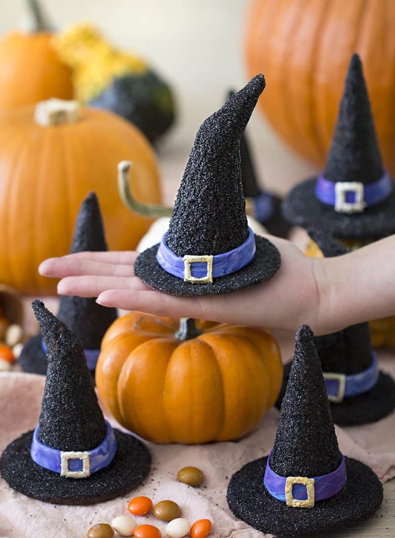 Photo of Witch hat cookie being held on a hand with pumpkins in the background