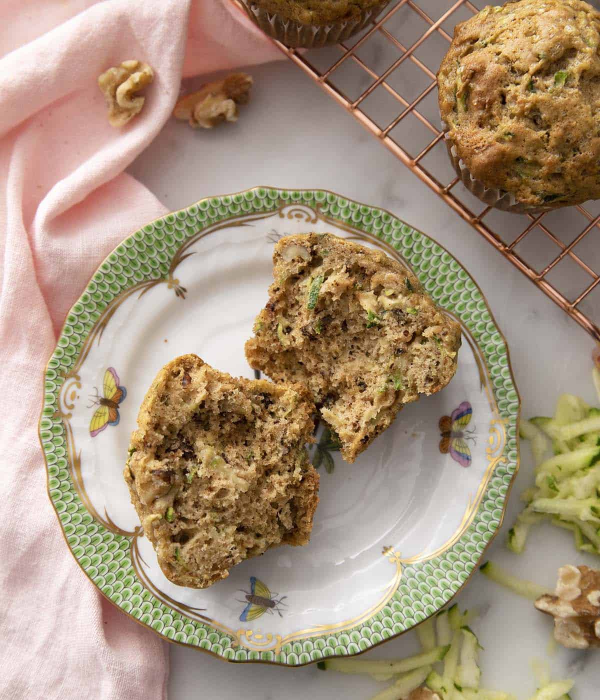 A zucchini muffin torn in half too show the delicious interior filled with walnuts.