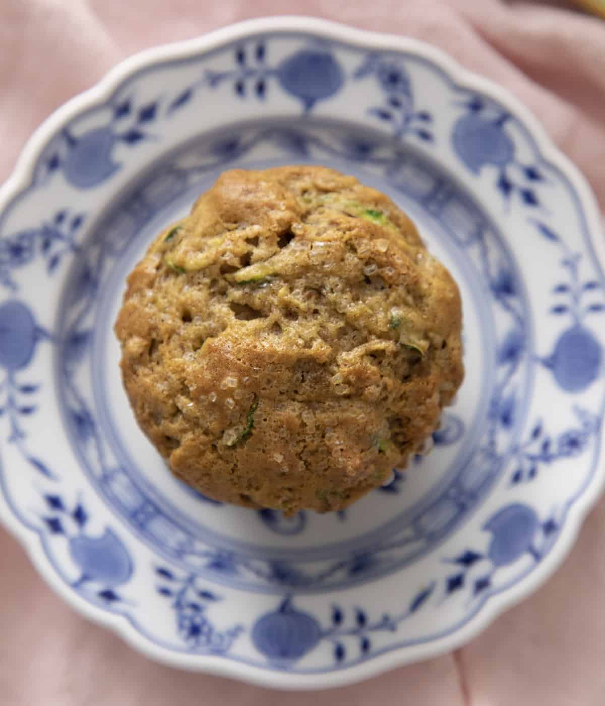 A top-down view of zucchini muffins on a blue and white plate. 
