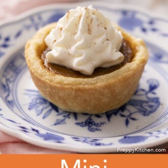 A mini pumpkin pie topped with a dollop of whipped cream on a blue and white plate.