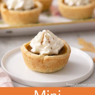 A mini pumpkin pie with whipped cream on a white plate.