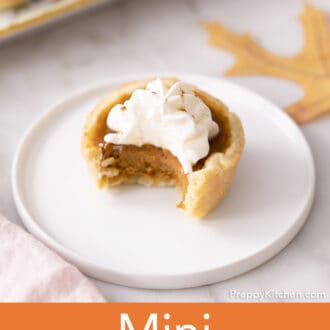 A mini pumpkin pie with a bite taken out.