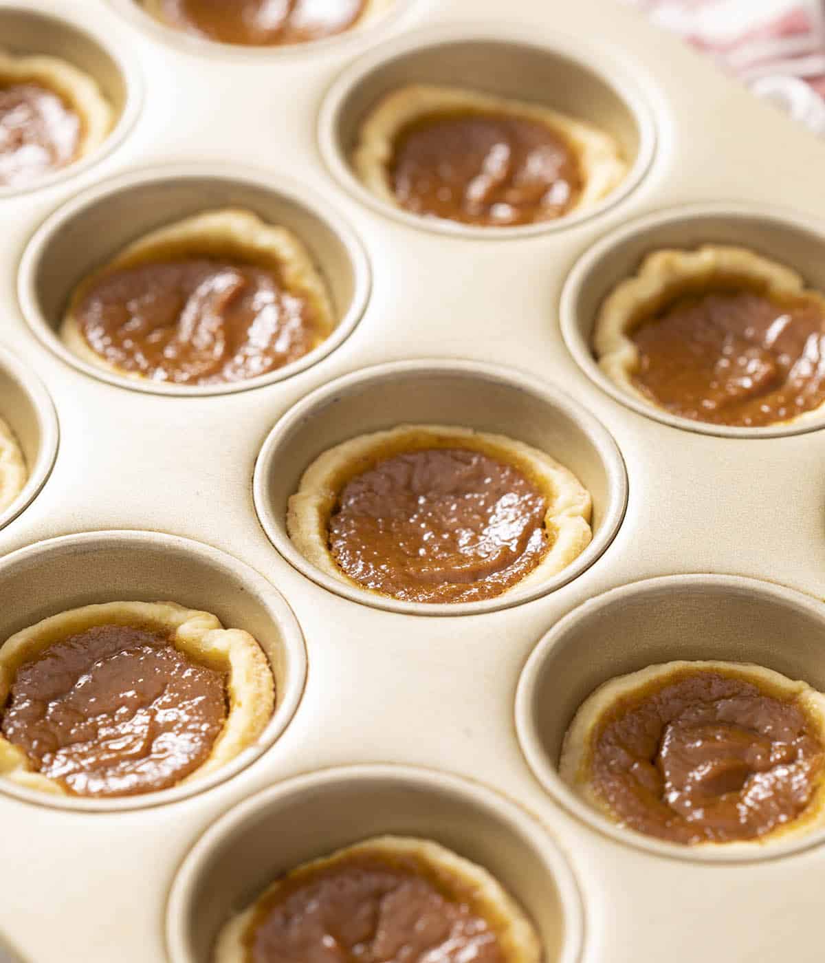 Mini pumpkin pies in a golden muffin tin just out of the oven.