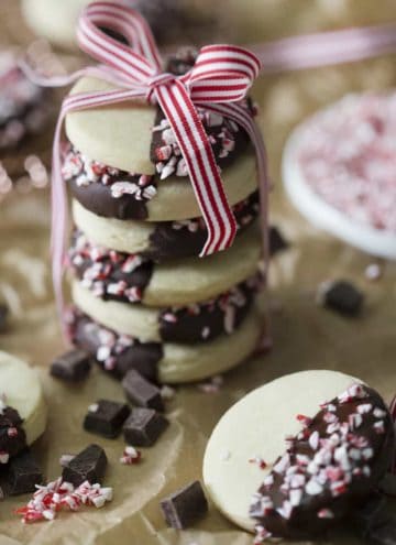 A photo of cookies that have been dipped in chocolate and peppermint, stacked on top of each other with a ribbon.