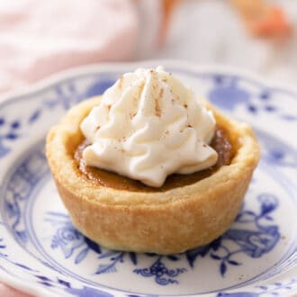 A mini pumpkin pie on a small blue and white plate.