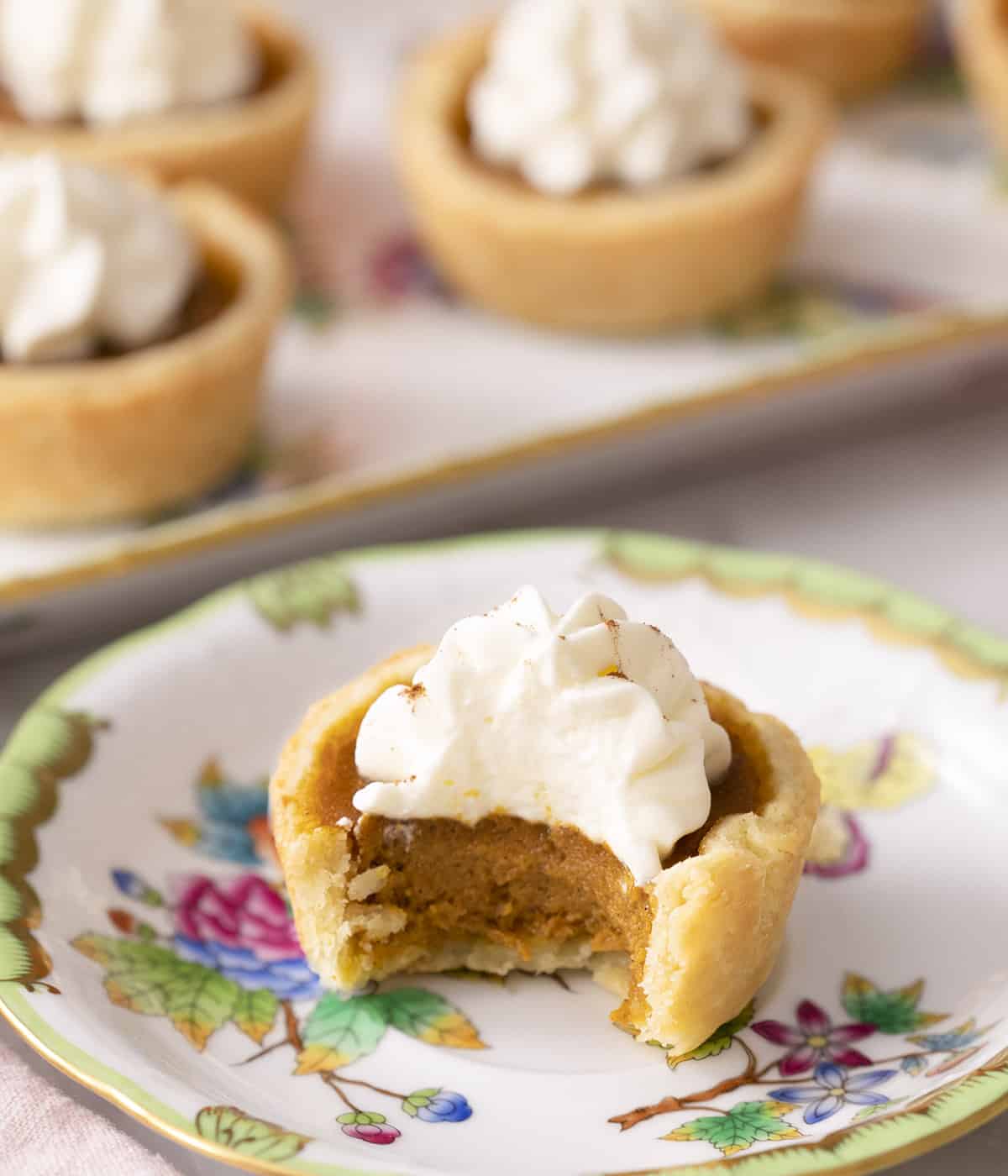 A mini pumpkin pie on a plate with a bite taken out.