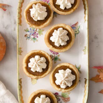 Mini pumpkin pies on a porcelain serving dish.