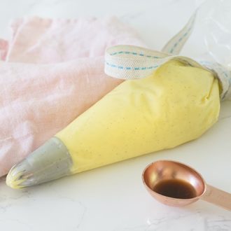 A photo of pastry cream in a piping bag on a white marble table.
