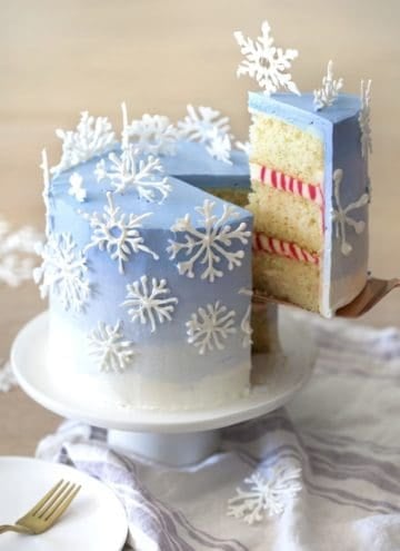 A photo of a piece being removed from a cake with snowflakes on top.