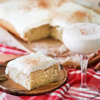 A piece of eggnog cake next to a glass of eggnog.
