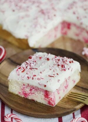 A photo showing a slice of Candy Cane Sheet Cake on a plate with crushed candy cane sprinkled on top.