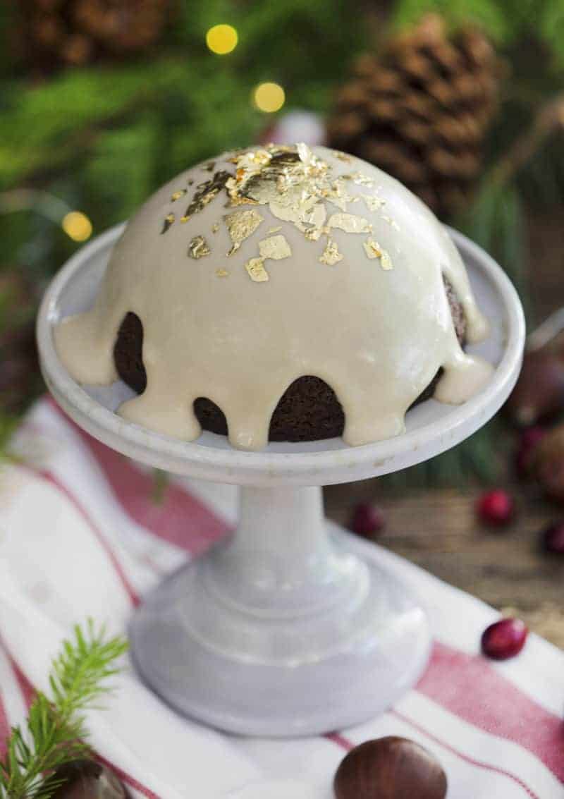 A photo of chocolate Christmas pudding on a mini cake plate with gold flakes on top