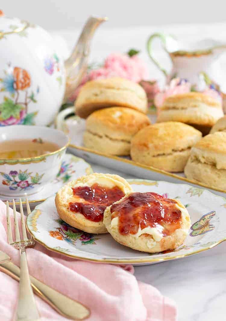 scones on a porcelain plate with a teapot next to them