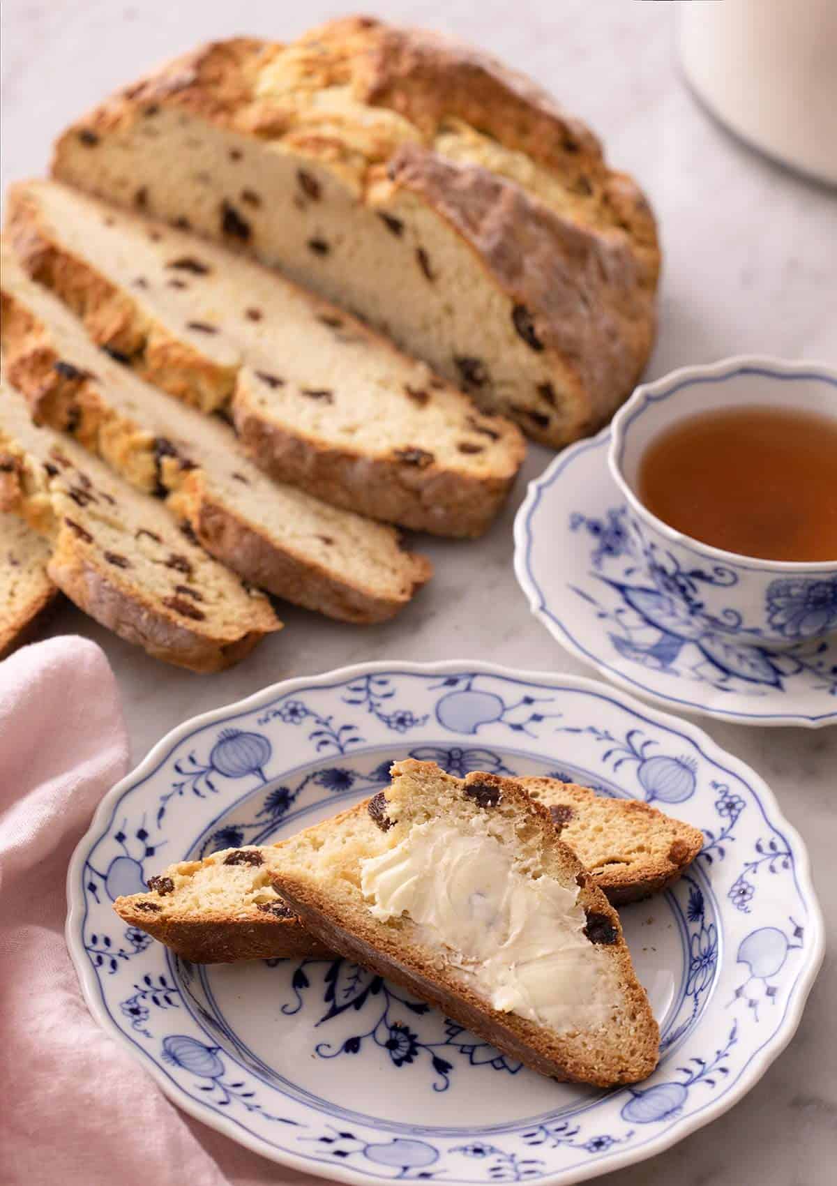 Slices of Irish soda bread spread with butter on a blue plate.