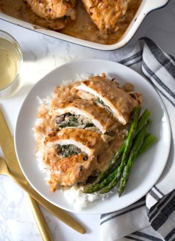 Spinach Stuffed Chicken Breast on a plate with rice and asparagus.