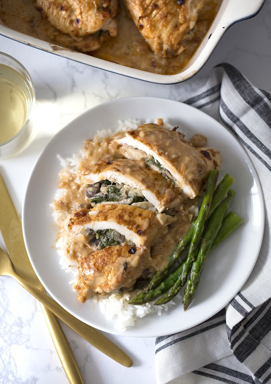 Spinach Stuffed Chicken Breast on a plate with rice and asparagus.