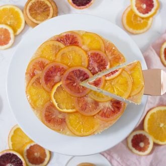 A photo of an Orange Upside down Cake with a piece being removed