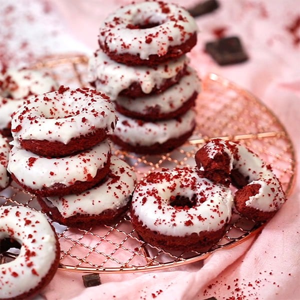 A photo of a group of red velvet donuts with one having been bitten into
