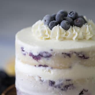 close up photo of Blueberry Lemon Cake topped with frozen blueberries