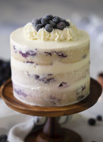 A lemon blueberry cake on a wooden cake stand