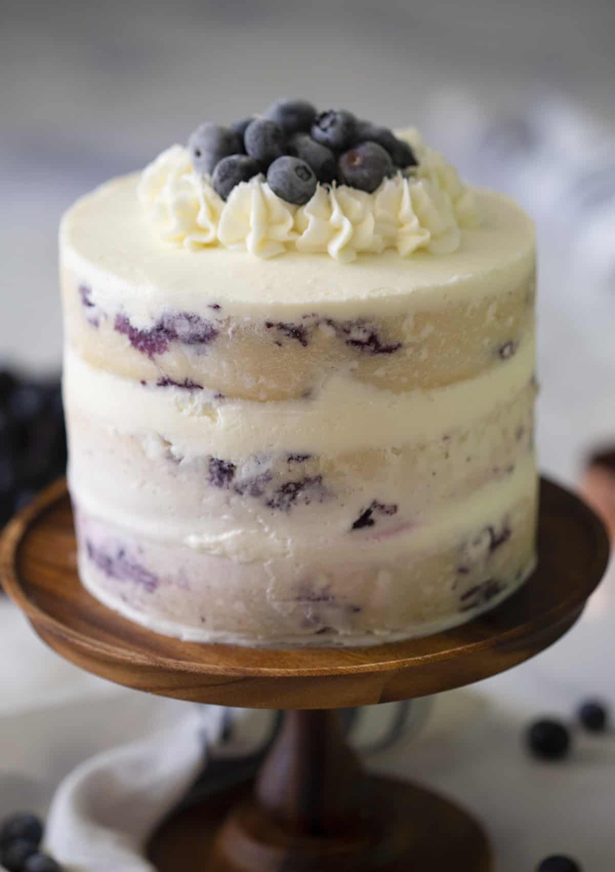 A lemon blueberry cake on a wooden cake stand