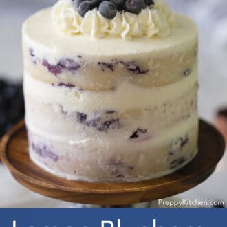 three layered lemon blueberry cake with white frosting on a stand