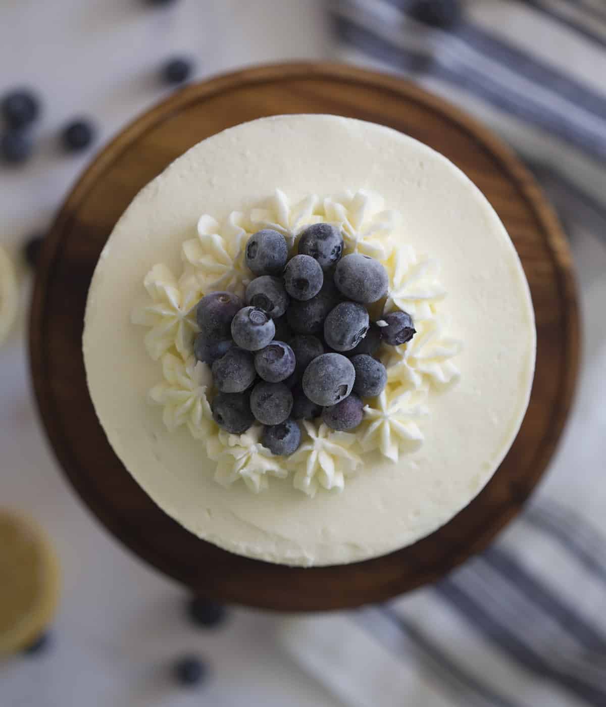 A top down photo of a lemon blueberry cake with frozen blueberries on top.