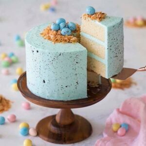 A slice of Easter egg cake cut and lifted from the rest of the cake on a cake stand.