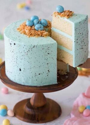 A slice of Easter egg cake cut and lifted from the rest of the cake on a cake stand.