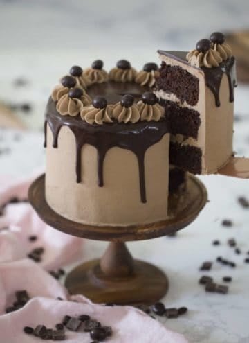 Photo of a Mocha Cake on a wooden cake stand with a pie being removed