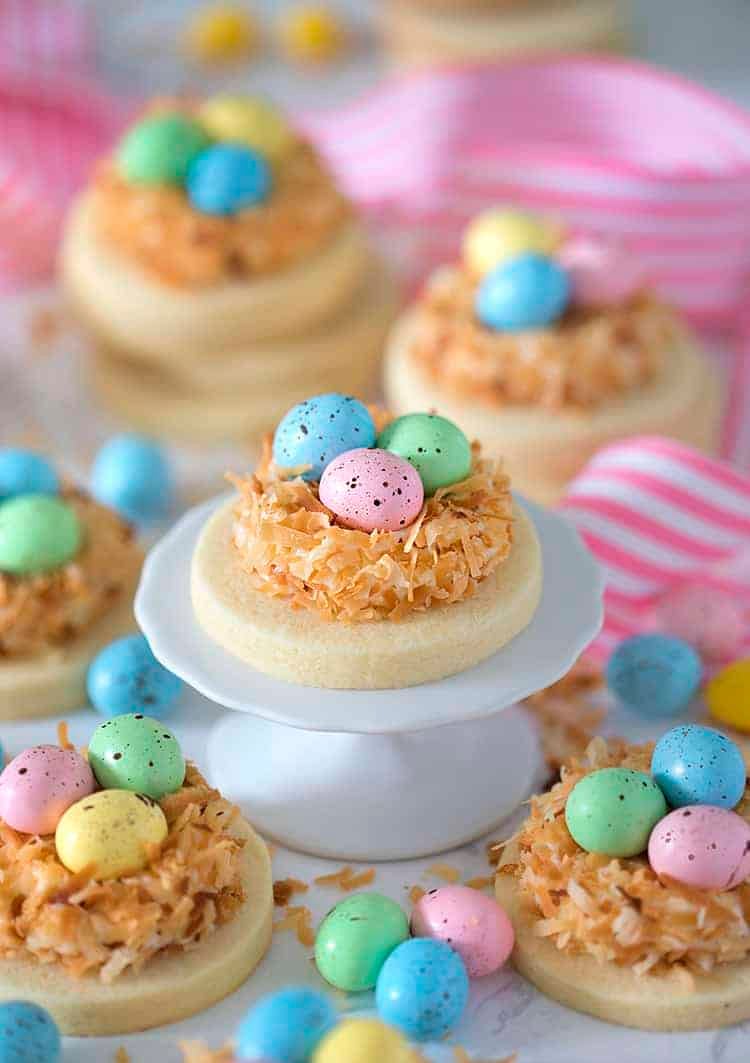 round sugar cookies topped with nests made with toasted coconut and candy eggs