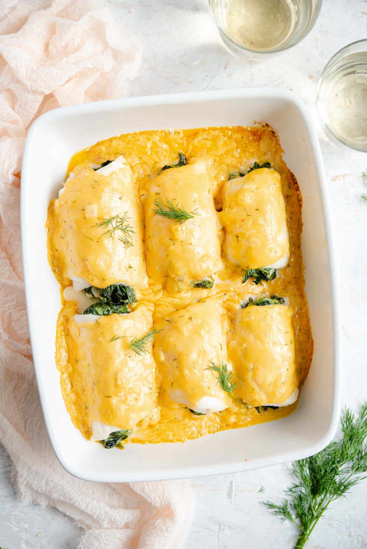 An overhead shot of baked fillet of sole in a baking dish with a cheese sauce