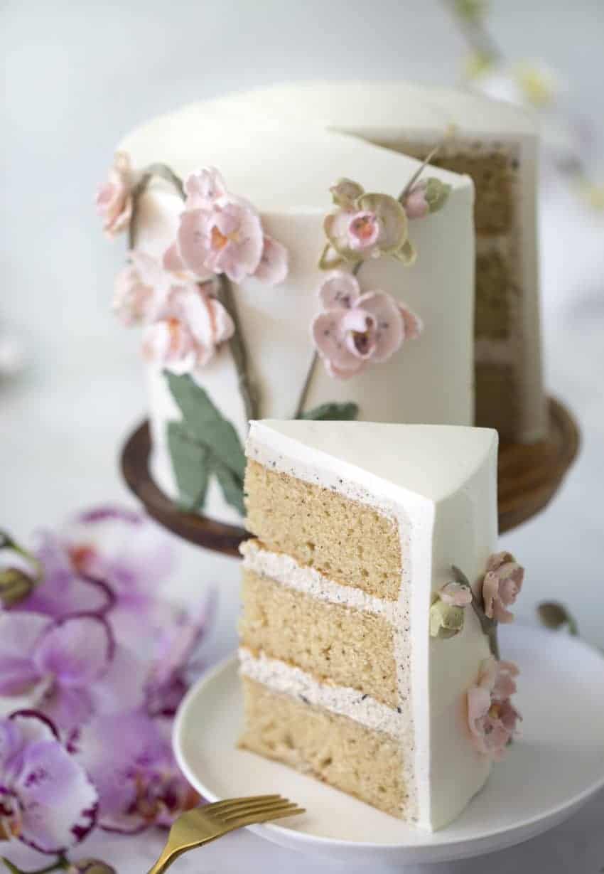 photo of a brown butter cake covered in buttercream orchids with a piece in the foreground