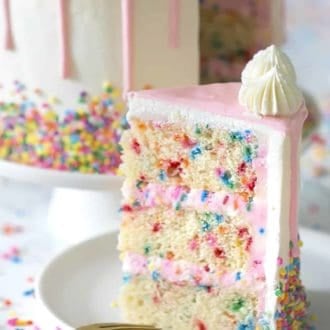 A piece of pink and white funfetti cake on a white plate.