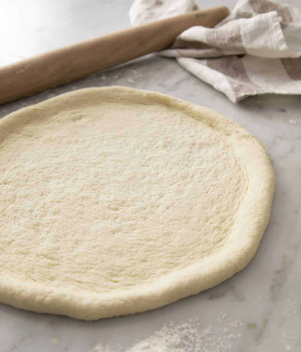 A pizza dough rolled out, ready for sauce and cheese to be added.