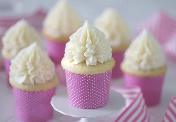 A group of vanilla cupcakes in pink and white polka dot papers