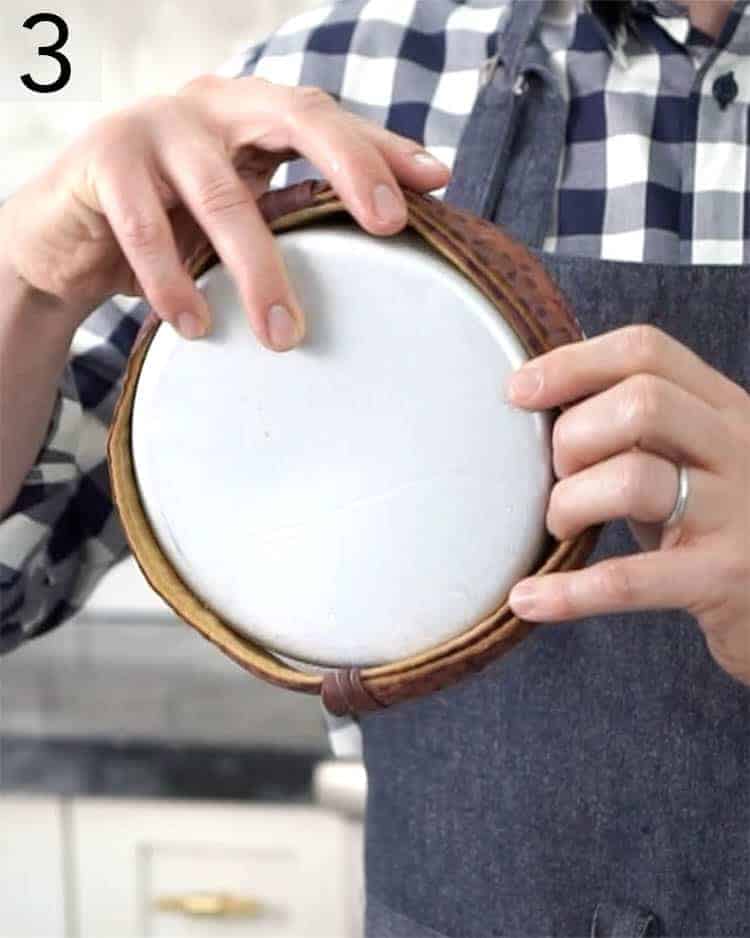 A damp fabric cake strip getting applied to a cake pan.