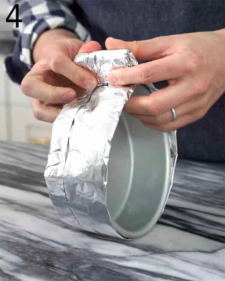 A homemade cake strip getting applied to the side of a cake pan..