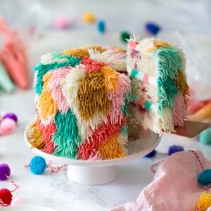 Photo of a shag cake on a white cake stand with a piece being removed