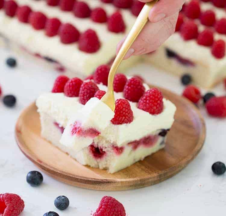 A bite being taken from an American Flag Cake made with blueberries and raspberries